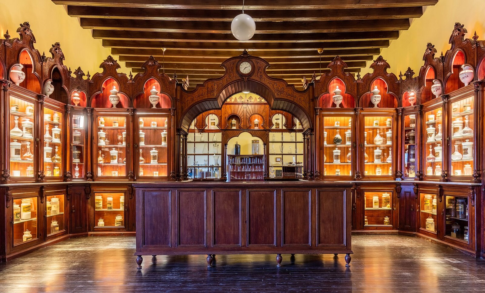 Toonbank met gevulde medicijnenkasten binnen in een Spaanse apotheek