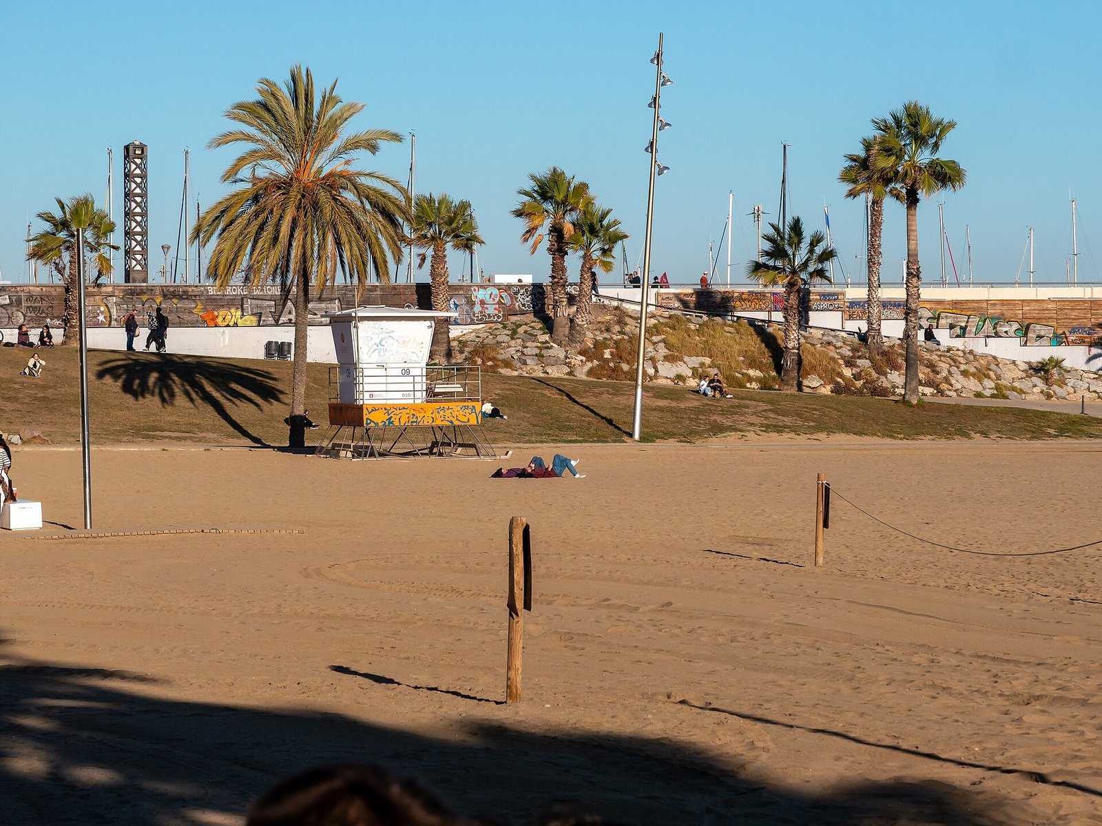 Zonnig strand van Barceloneta met wandelaars langs de brede boulevard