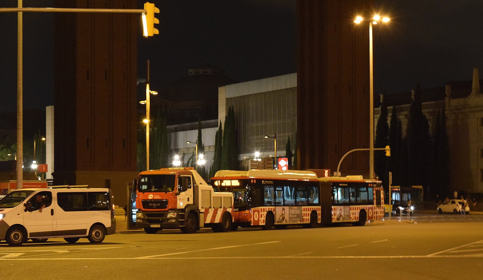 Stadsbus wacht bij een halte in een nachtelijke straat in Barcelona